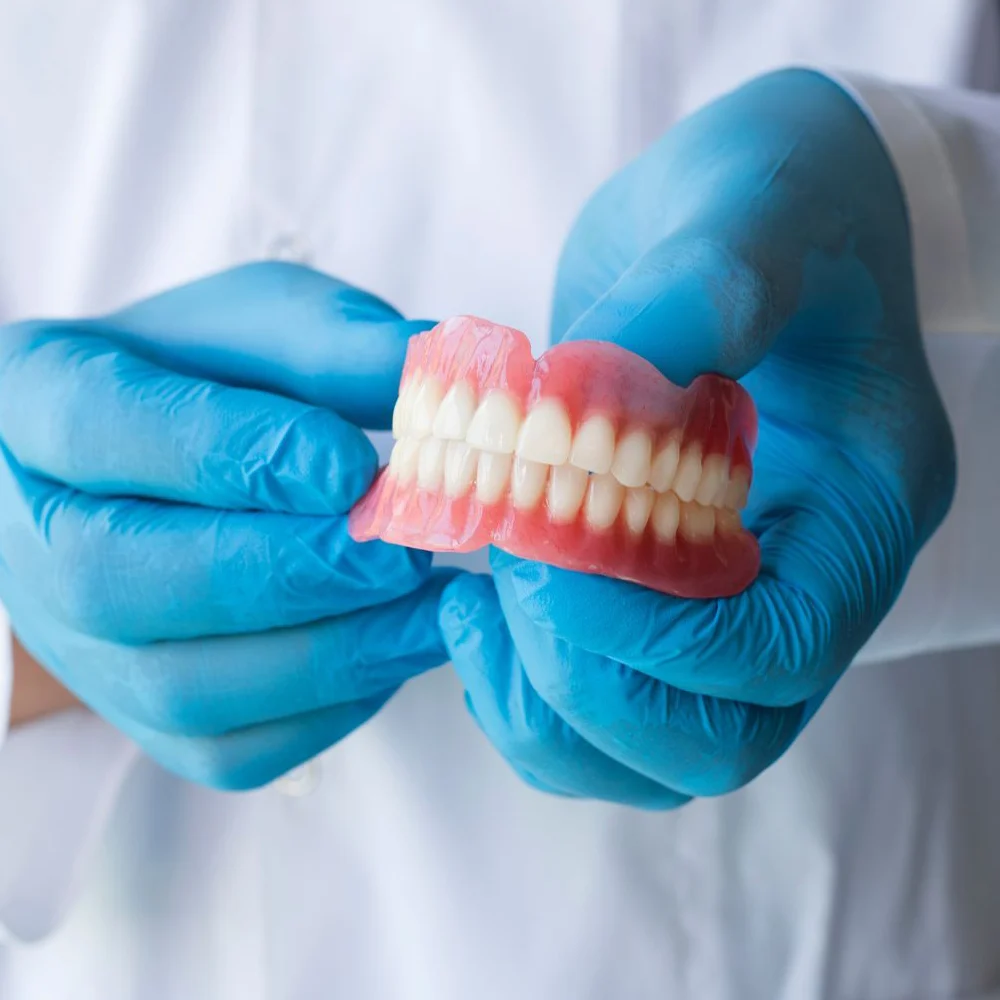 Dentist Holding Traditional Dentures
